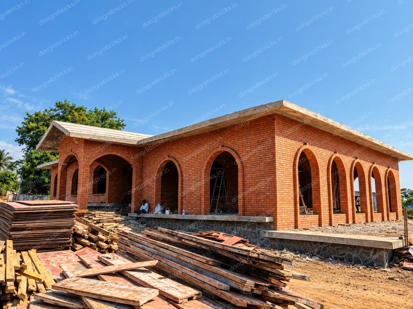 Single-storey arched brick building under construction on a stone plinth
