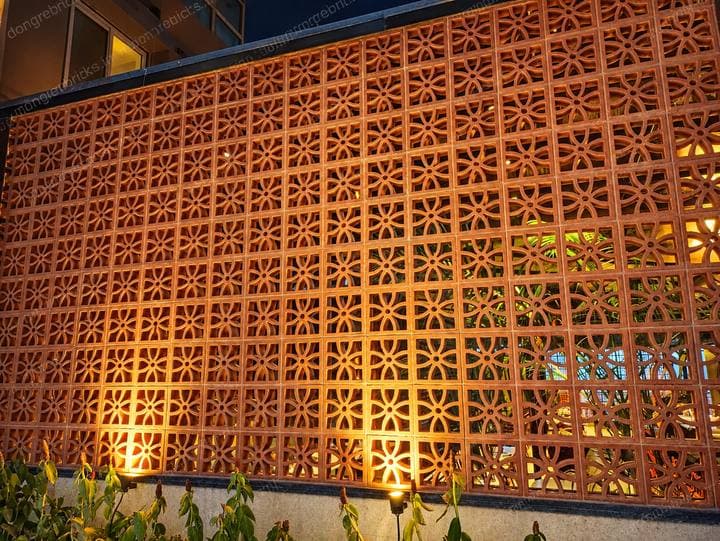 Decorative moulded terracotta jali screen, floral perforation, lit at night